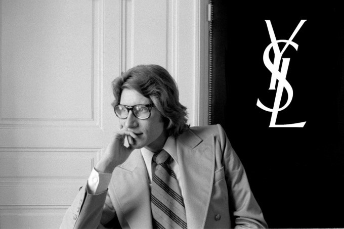 Yves Saint Laurent devant le logo de la marque qu'il a fondée en