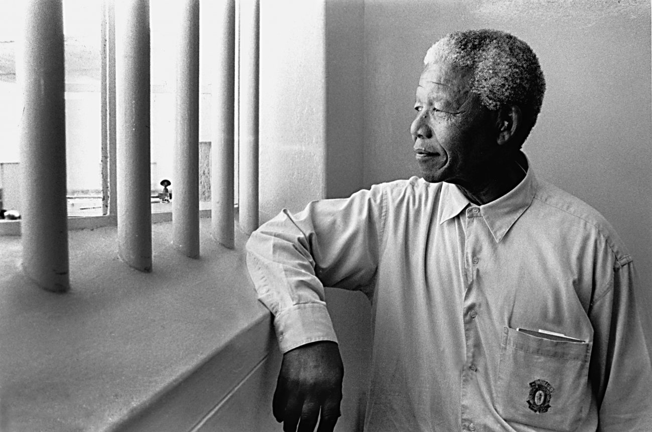 Le prix Nobel de la paix accepte de poser dans la cellule où il a passé 18 de ses 27 années d'emprisonnement. Robben Island, Afrique du Sud, 1994, image © Jürgen Schadeberg