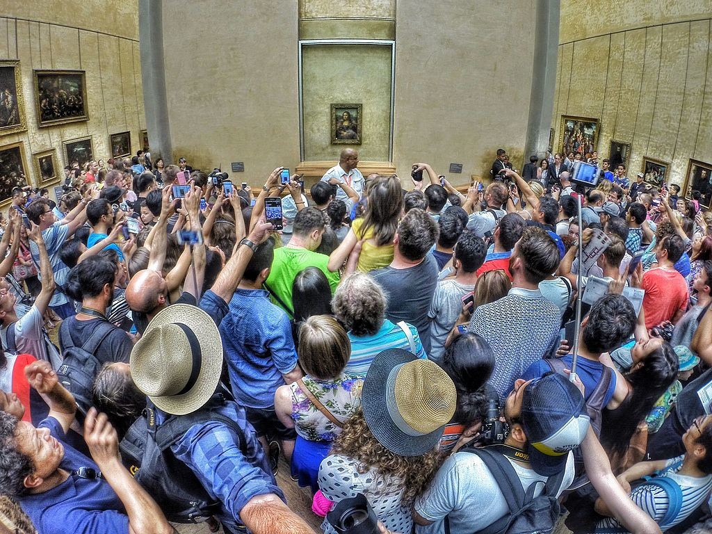 Des visiteurs se pressant devant la Joconde de Léonard de Vinci Image via Wikipédia