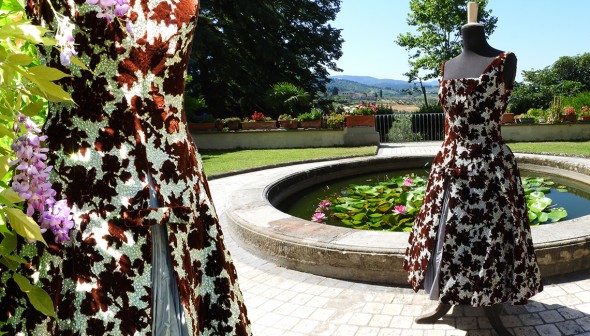 Silbernes Seidenkleid mit Petticoat und weinroten Samtblumen. Foto im Park der Villa in Chianti aufgenommen.