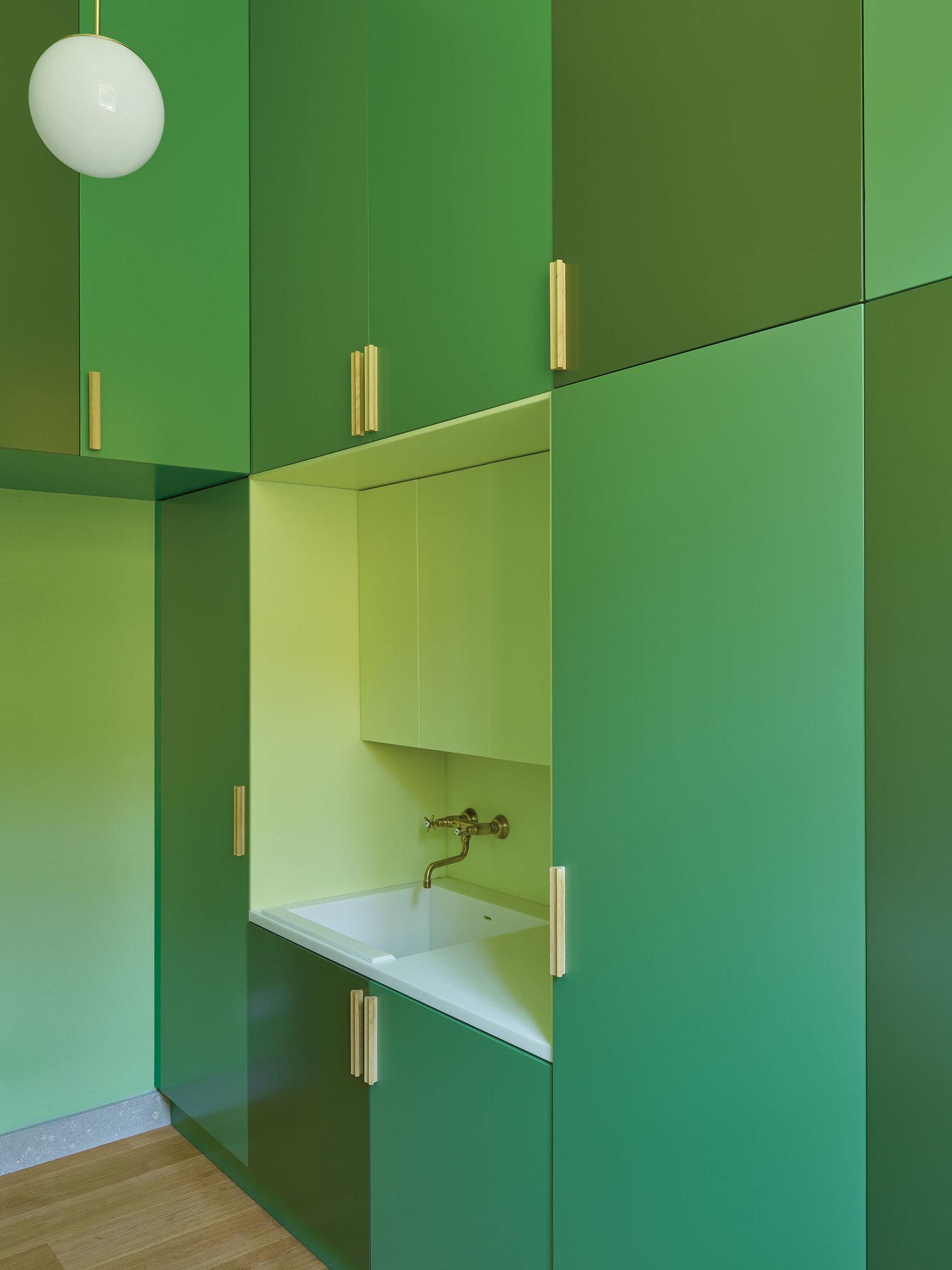 Opaque lacquered cabinets in shades of green in the laundry room