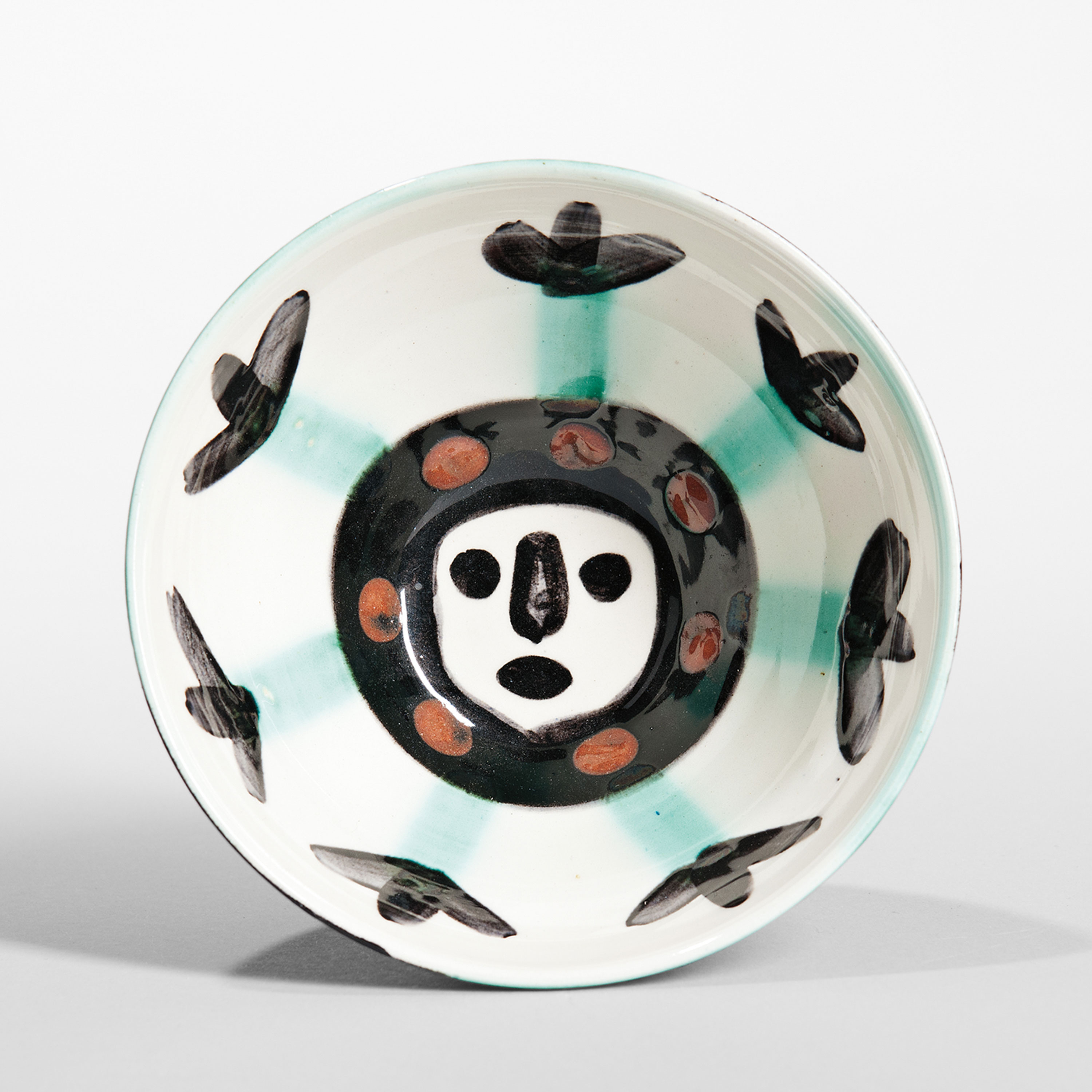 Pablo Picasso (1881-1973) Visage Bowl Glazed ceramic 1955 Madoura round cup of white clay hand-decorated in engobes, black, green, and brick red underglaze, marked Edition Picasso Madoura, ht. 2 1/2, dia. 5 1/8 in.