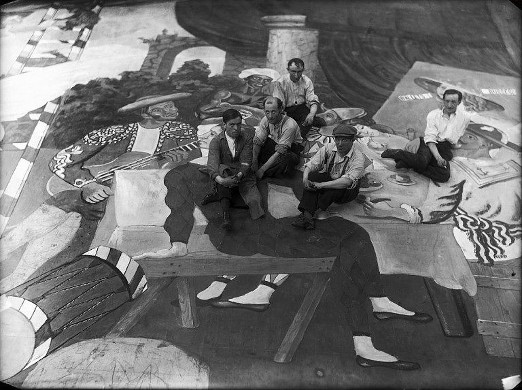 Pablo Picasso (second from the right, wearing a cap), surrounded by stage workers during the preparations for the ballet "Parade." Photo via Wikimedia Commons