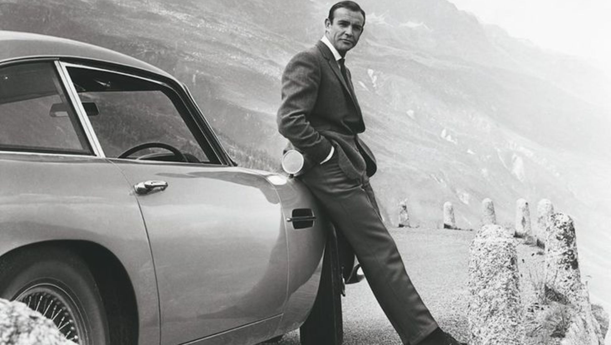 Actor Sean Connery poses as James Bond next to his Aston Martin DB5 for movie 'Goldfinger", 1964 - Photo by Donaldson Collection - Michael Ochs Archives via Barneby.fr