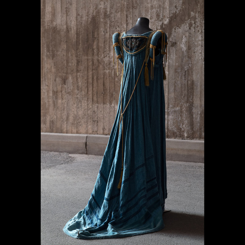 Operan Rigoletto hade premiär den 12 september 1987 på Kungliga Operan. Design Agneta Skarp och regi Georg Malvius. Klänning i blått råsiden med metallbandsbesättningar. Buren av Prinsessan Madeleine 2001 på Kungaparets silverbröllopsfest. Storlek medium. Utrop 4-5 000 kronor