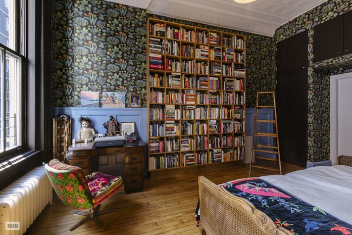 Våga mönster! Tapet av Josef Frank för Svenskt tenn, böcker i mängder, säng med rotting och en omklädd fåtölj i 50-tals modell. Bild via Brown Harris Stevens.