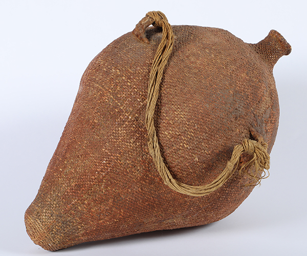 Camp-size, vintage Washoe water pack basket “Tus” in a sacred red ochre color, 20 inches tall, 12 inches diameter, with close twined willow and hemp handles ($2,000).